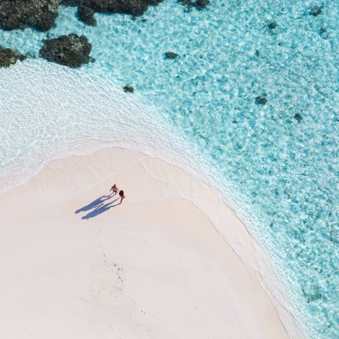 drone view of adult couple on a beach, maldives