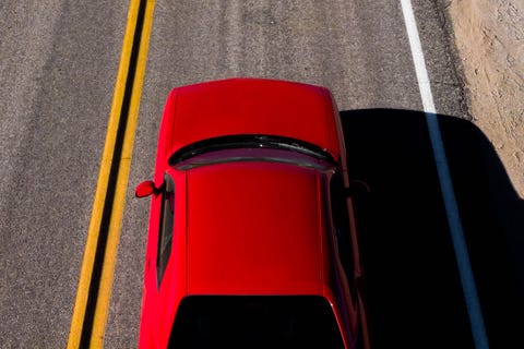 drone view of american car driving in a straight road at the california desert