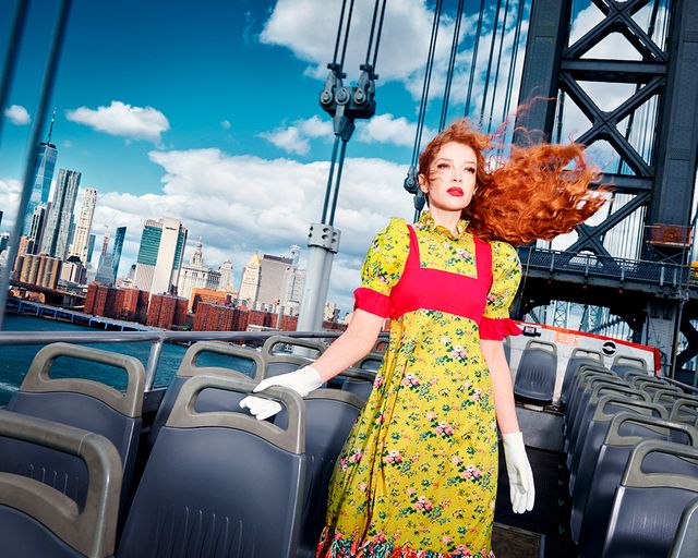 batsheva hay stands on top of a double decker bus wearing a dress from the batsheva x laura ashley summer 2022 collection featuring puff sleeves and contrasting floral fabrics