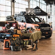 a pile of gear next to an orange car parked by a small booth inside a building