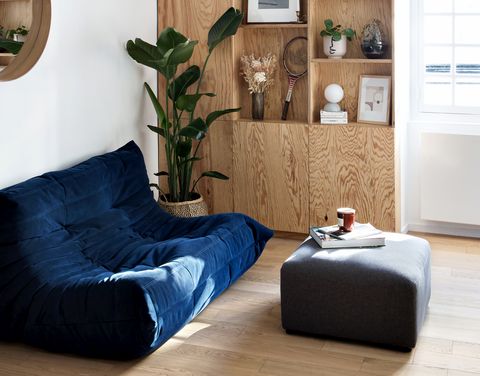 salón con estantería de madera y sofá togo de terciopelo azul