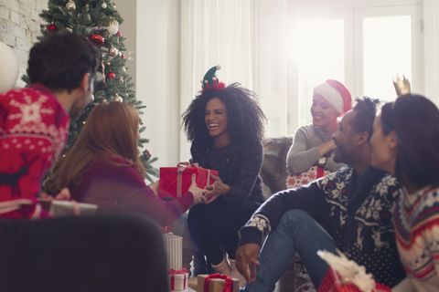 Smiling friends exchanging Christmas gifts in living room