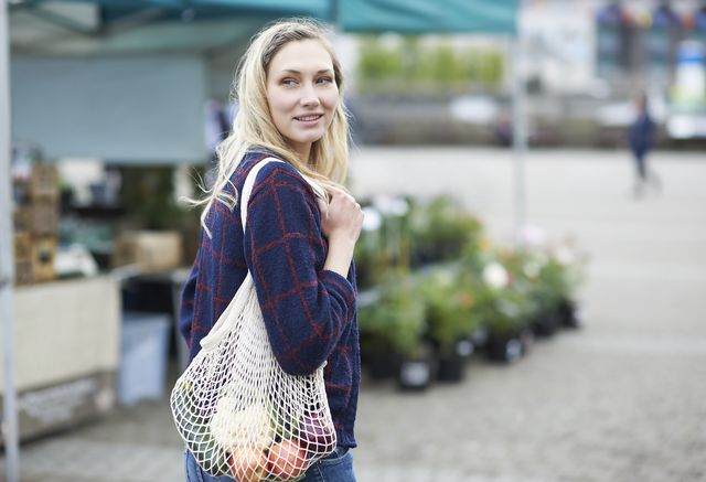 a woman shopping for fruit and vegetables on a local market with a reusable plastic free bag