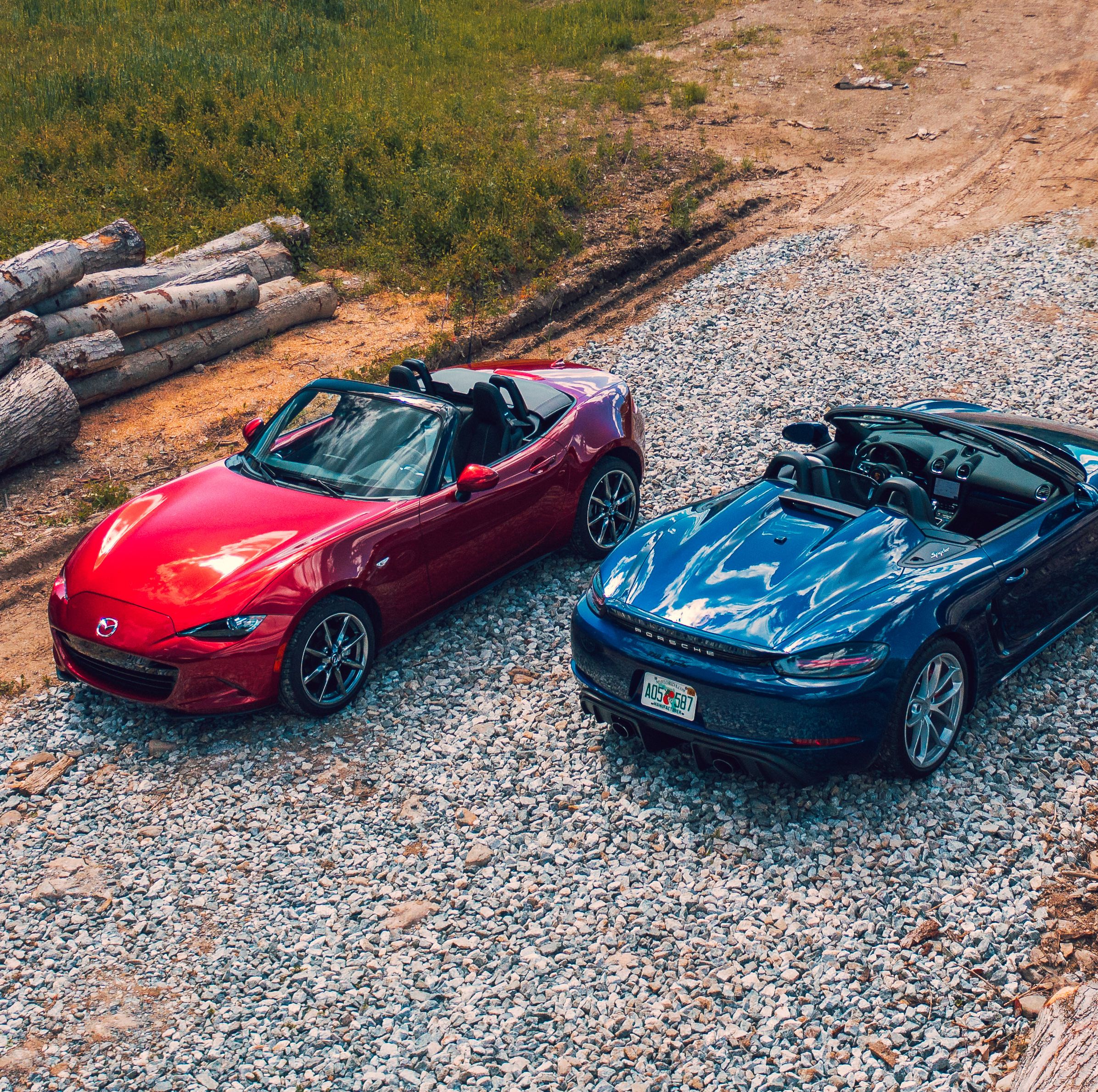 red Mazda Miata and blue Porsche Boxster parked side by side