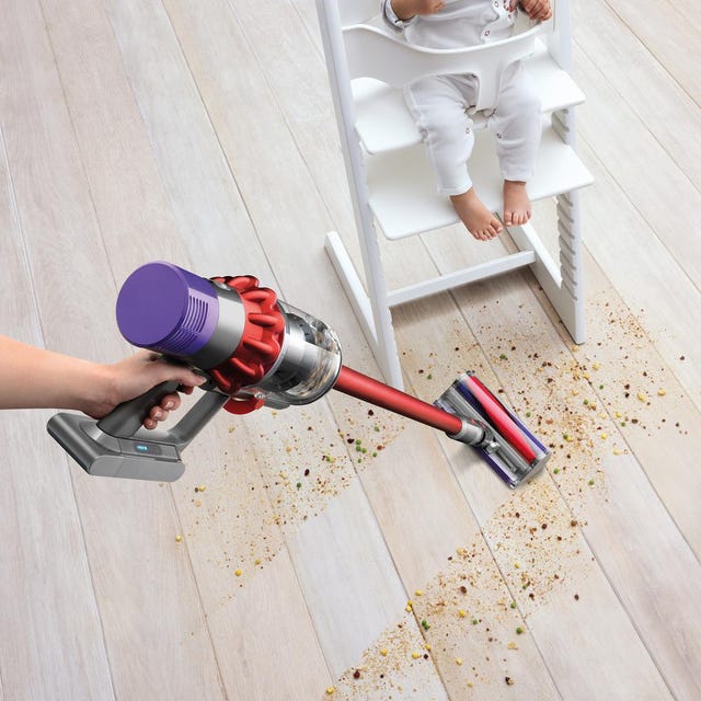 Dyson Cyclone V10 Motorhead Cordless Stick Vacuum a vacuum cleaner cleaning up a mess underneath a baby in a high chair