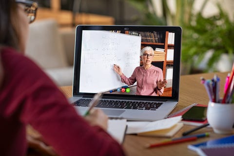 Studying with video online lesson at home young student watching lesson online and studying from home young woman taking notes while looking at computer screen following professor doing math on video call latin girl student studying from home and watching teacher explaining math formula on video chat