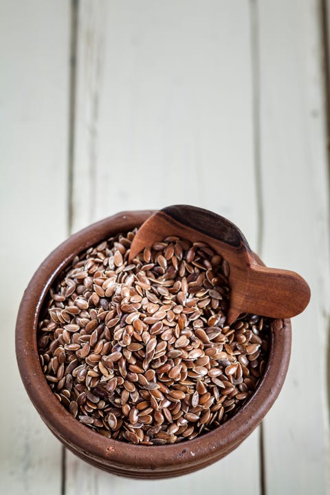Earthenware dish of organic linseed, Linum usitatissimum, on white wood Earthenware dish of organic linseed, Linum usitatissimum, on white wood