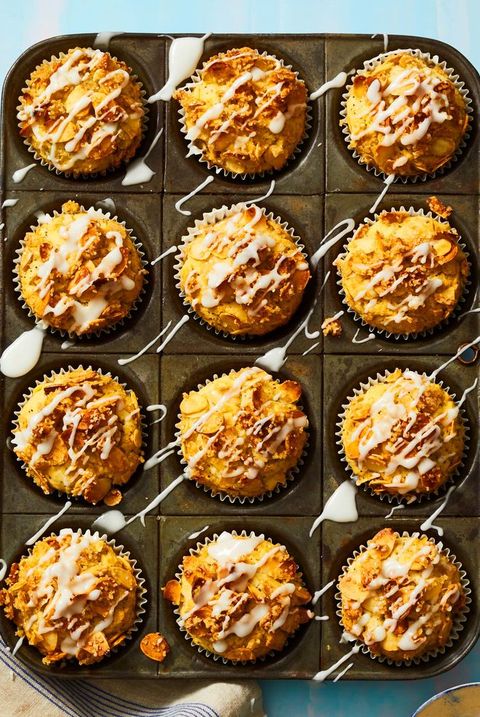 lemon almond poppy seed muffins in a muffin tin with icing drizzled on top