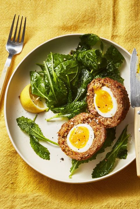 scotch eggs with a side of green salad on a white plate