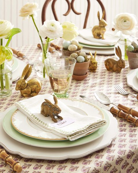 an easter table with brass bunnies at each place setting holding placecards and also down the center of the table creating a centerpiece