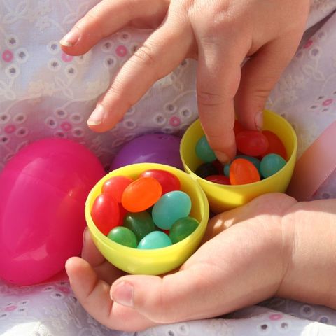 child hands holding plastic easter egg filled with jelly beans