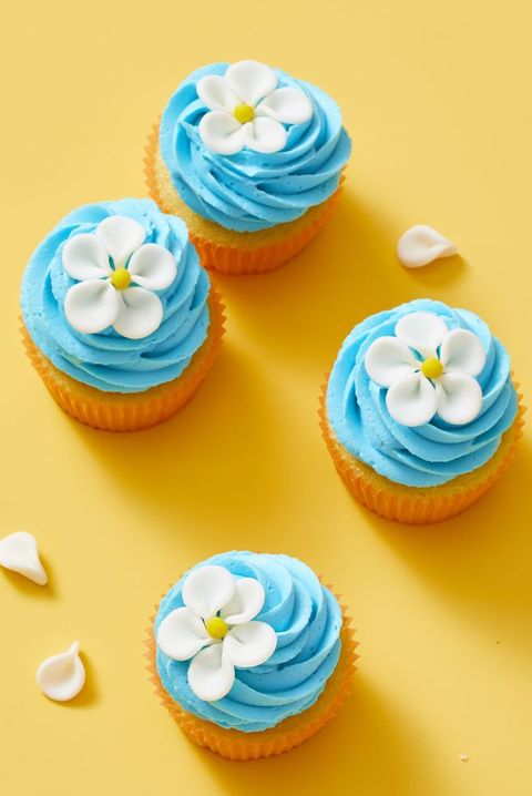 vanilla cupcakes with blue frosting and a white flower on top