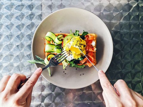 eating brunch with waffle, avocado, cucumber, salmon and poached egg, personal perspective