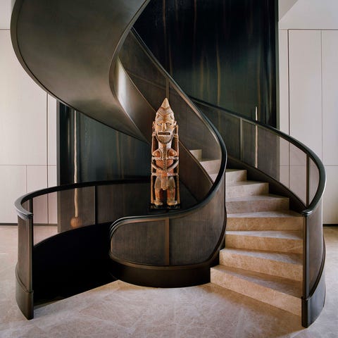 sweeping staircase with an african totem at center