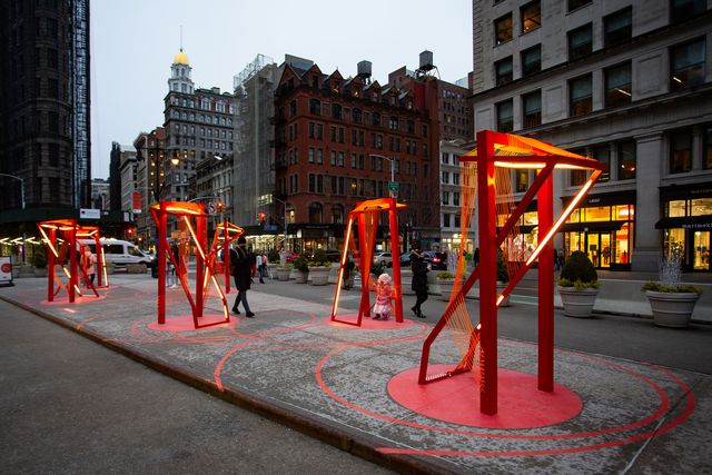 red lighted sculpture installation on the street in new york city at the flatiron building plaza