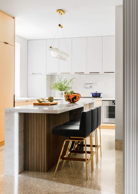 kitchen with white cabinets and island in the middle with white marble top and black leather backed stools pulled up to it