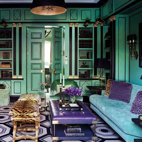 teal room with matching blue velvet sofa with purple design pillows and purple and black rug and purple tufted top coffee table and a tiger patter x stools