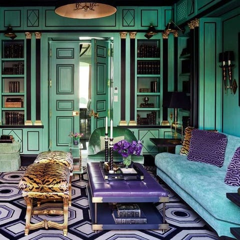 A List 2022 - ELLE DECOR teal room with matching blue velvet sofa with purple design pillows and purple and black rug and purple tufted top coffee table and a tiger patter x stools