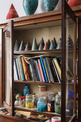 a small cabinet with shelves containing cone-shaped studies and jars filled with colored paint