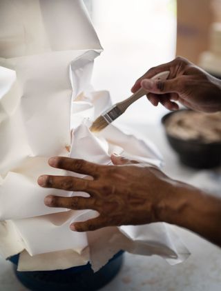 close up of artist hands working on paper lantern fixture