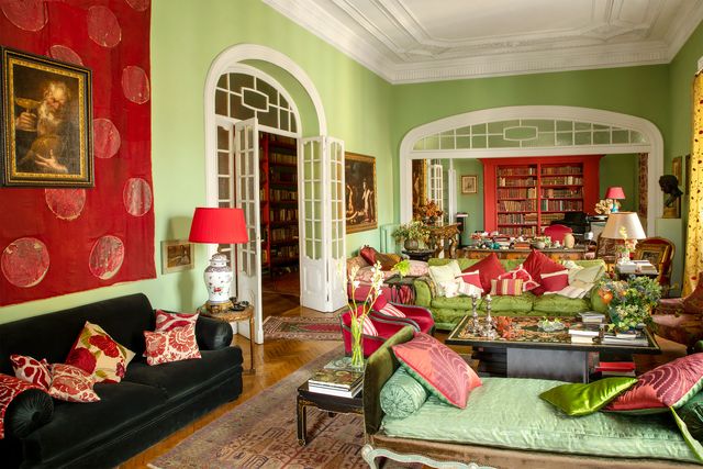 living and sitting rooms with pistachio green walls and red accents with arched doorways, a sofa covered green silk, turkish rugs, and a chinese side table