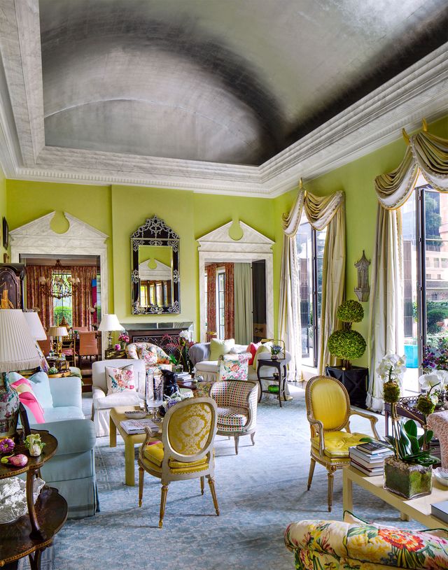 highly decorated living room with lime green walls and tall windwos with light yellow green draperies and arched doorways and lots of colorful furniture and a blue faded carpet beneath