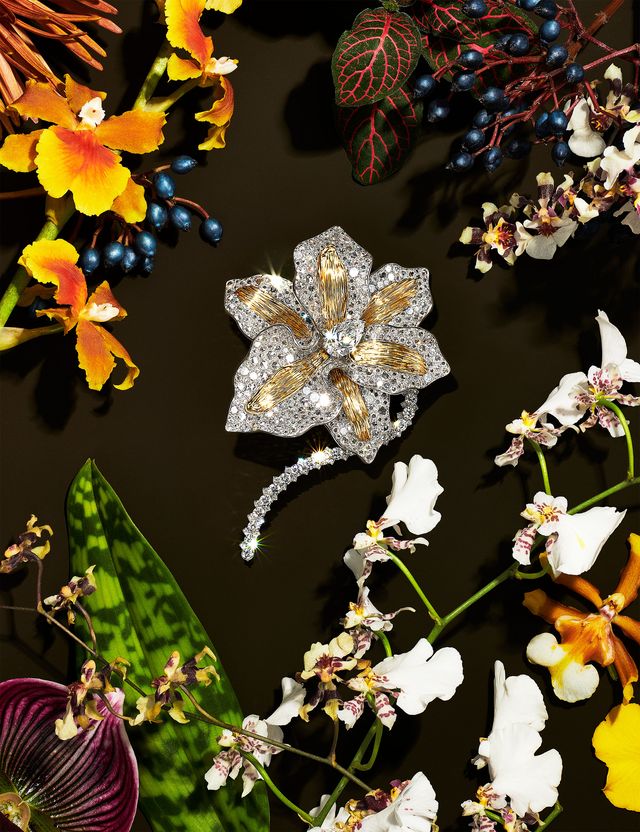 orchid pendant inlaid with diamonds and gold surrounded by ornamental flowers