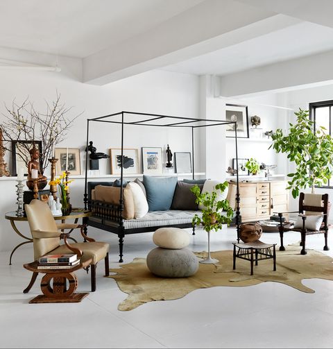 living room with a daybed, armchairs, sofa, cowhide rug, footstool and pouf, with three large windows, white walls and ceiling and white painted floor
