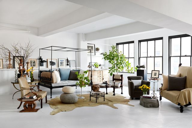 living room with a daybed, armchairs, sofa, cowhide rug, footstool and pouf, with three large windows, white walls and ceiling and white painted floor