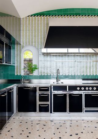 cocina moderna con gabinetes negros y plateados y paredes de azulejos verdes