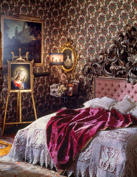 bedroom with patterned wall covering, easel print of virgin mary, and large bed
