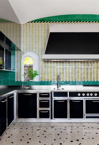 Kitchen with mottled floor and green tiled wall behind the counter