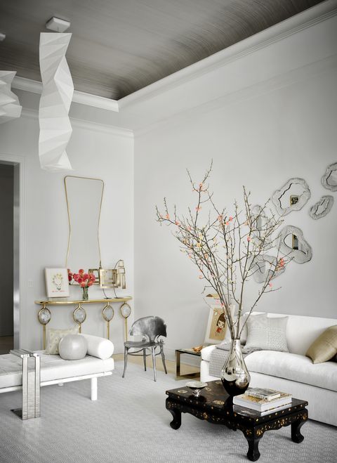 aman and meeks living room with white furniture, large mirror, and branches in vase