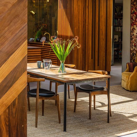 wooden table on a sisal rug in an open room with wooden textured walls