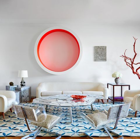 dining area with white round table at center with chairs sofa against wall and a large round pink and white piece of art on the wall