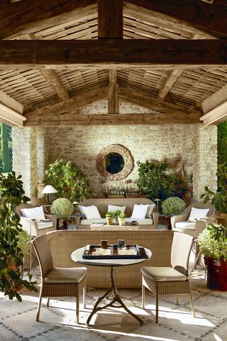 outdoor living room with beamed ceiling, wicker furniture and large mirror