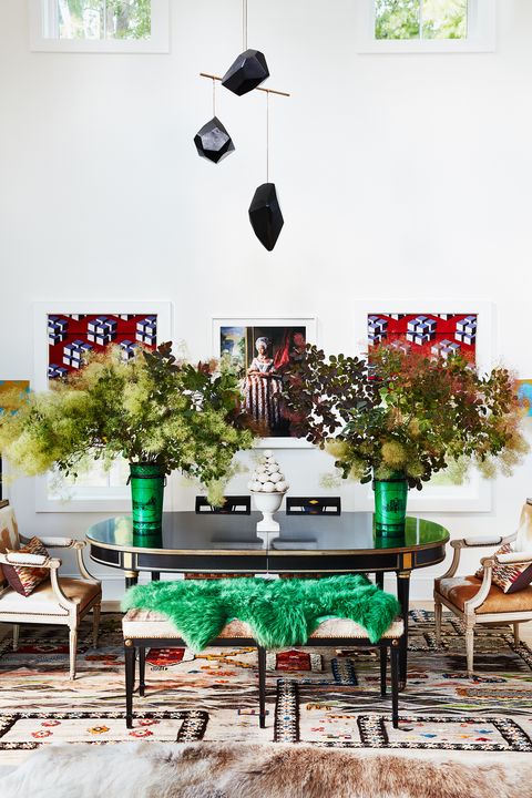 center dining table with large vases with flowers in a high ceiling room with an art mobile hanging from above