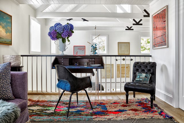 landing with small table, rug, and chairs overlooking room with art on walls