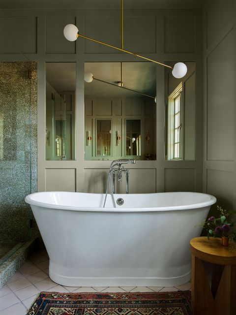 deep standalone white tub in a smallish space with paneled wall with mirrors behind it