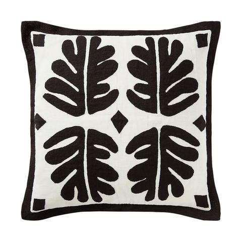 white pillow with black edging and four black leaflike designs and diamonds at center
