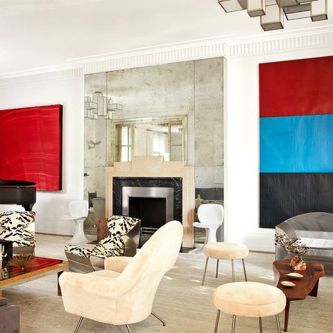 living area with multiple kinds of chairs in cream velvet and tiger striped and two large color block pieces of art on the walls