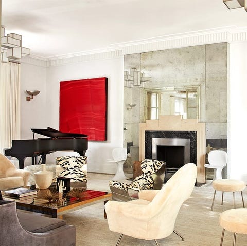 living area with multiple kinds of chairs in cream velvet and tiger striped and two large color block pieces of art on the walls