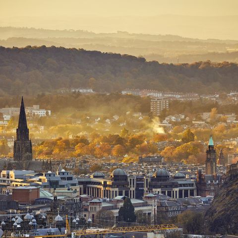Edinburgh cityscape and mountains on skyline with St Mary's Cathedral steeples and Autumn trees