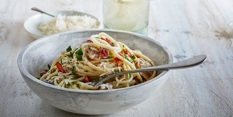 Eenpersoons gerecht: Pasta met kip doperwten zongedroogde tomaatjes pasta in een rustieke schaal