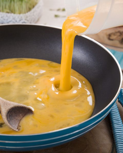 liquid egg for scrambled eggs is being poured into frying pan