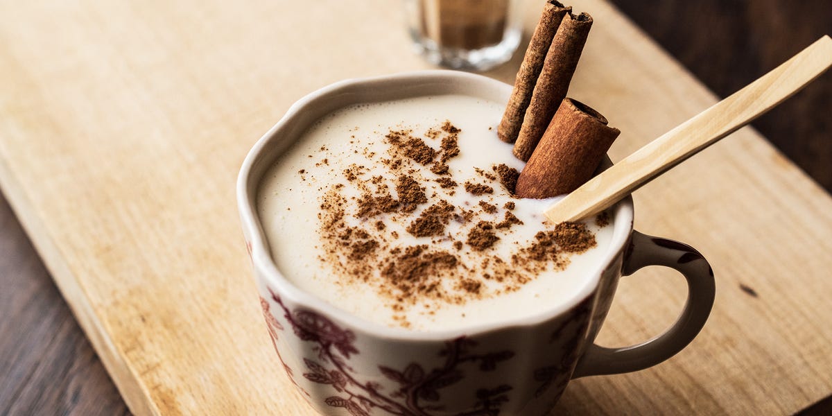 A glass of eggnog with a cinnamon stick