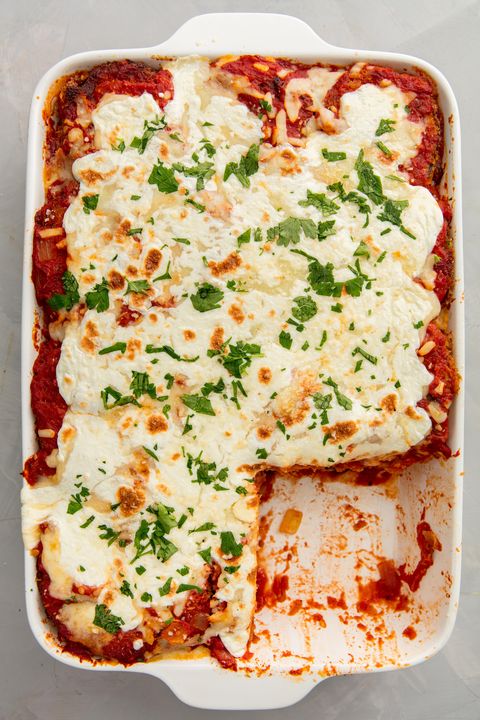 eggplant parmesan in a white baking dish with one piece cut out