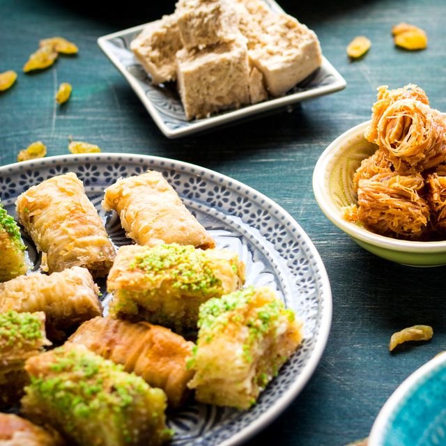 eid al fitr food set of assorted traditional eastern desserts and sweets on wooden table baklava, halva, rahat lokum, sherbet, nuts, pistachios, dates, raisins, kadayif on colorful plates