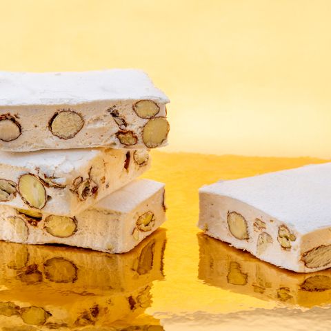 eid al fitr food nougat with almonds and hazelnuts on a golden background where it is reflected