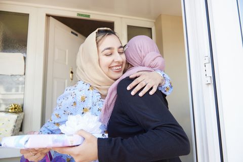 Seorang wanita muda menyambut temannya dan memeluknya pada Idul Fitri